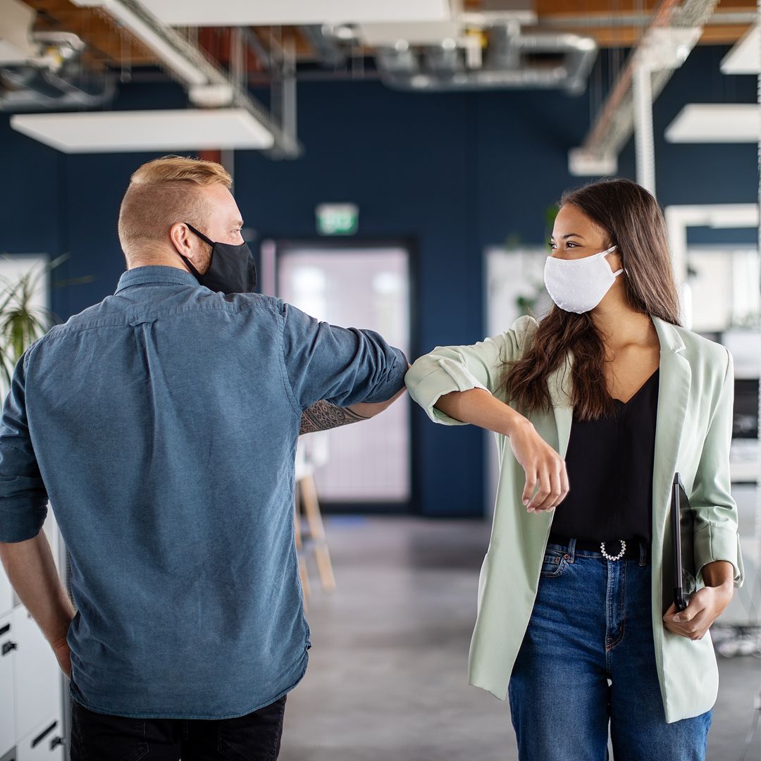 coworkers bumping elbows in office